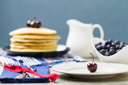 A table laid with blueberries and a stack of pancakes
