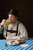 A stereotypical German man wearing lederhosen and eating white sausage with beer