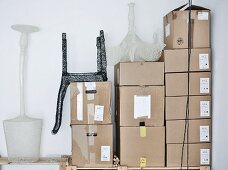 Mesh sculptures of designer lamps and chair on stacked shipping cartons in corner