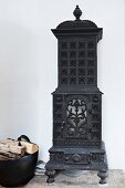 Antique, cast iron, wood-burning stove against white wall
