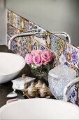 Detail of washstand with designer, wall-mounted taps and tiles in various Oriental patterns