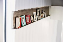 Framed pictures on narrow shelf formed by recess in wall