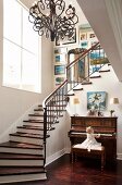 Spacious stairwell with winding staircase and wrought iron chandelier; little girl playing on piano