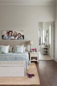 Bedroom in natural shades with picture of family and open door leading to ensuite bathroom