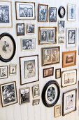 Gallery of retro-style family photos in various frames on white wooden wall