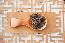 Pu-ehr tea leaves on a wooden spoon