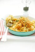 Cheese Spätzle (soft egg noodles from Swabia) with fried onions in an enamel baking dish