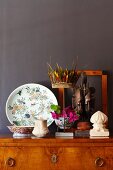 Antique collectors' items on antique cabinet against dark brown wall