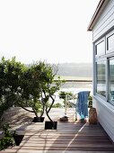 Ferienhaus mit Holzterrrasse und Ausschnitten für Baumäste, Blick über Lagunenlandschaft