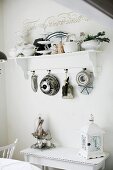 Cake tins hanging from bracket shelf above vintage lantern on console table