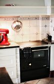 Black, vintage kitchen cooker against white splashback with accent tiles in simple kitchen