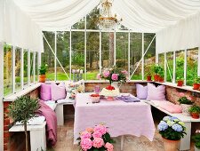 Dining area decorated in shades of lilac with U-shaped bench in conservatory