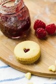 Homemade Jammie Dodgers and raspberry jam on a floured wooden board