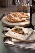 Slice of pizza on wooden board and cut pizza in background