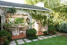 Potted climbing plants in front of roofed terrace with inviting seating area