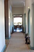 Narrow hallway with runner and open double doors at far end with view of dining area