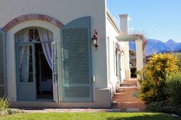 Mediterranean country house with arched door and open shutters painted grey-green