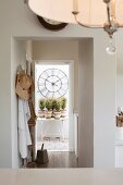 View of open terrace door through wall aperture; potted plants on garden table below vintage wall clock