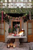 Weihnachtlich geschmücktes Haus und Terrasse mit antikem Steintisch und Bodenlaternen
