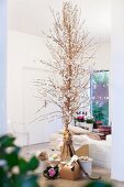 Gifts below delicate Christmas tree made from palm fronts decorated with white paper flowers