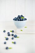 Fresh blueberries in a white bowl and in front of it