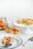A sliced apricots pie with slivered almonds, one slice on a plate