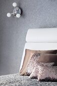 Grau und Taupe als elegante Farbergänzung zum weissen Kopfteil eines Doppelbetts; darüber eine Wandleuchte mit kleinen Kugelschirmen