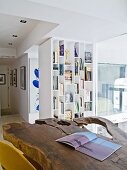 Rustic, live edge wooden table top in modern living room with white shelving in background