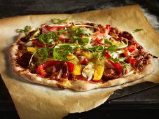 Hausgemachte Pizza mit Paprika, Peperoniwurst und Rucola