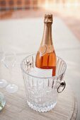 Close-up of flutes and wine bottle in ice bucket on table