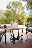 Vase and wine bottle in ice bucket on outdoor table in front of plants