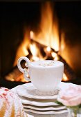 Eine Tasse Cappuccino vor dem Kaminfeuer