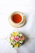 A cupcake decorated with romantic sugar flowers with a cup of tea