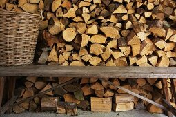 Rustic wooden bench and wicker basket in front of stacked firewood