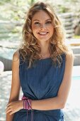 A young blonde woman outside wearing a blue summer dress