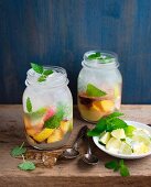 Selbstgemachte Limonade mit Früchten, Eiswürfeln und Zitronenmelisse