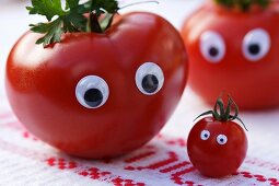 A tomato family with eyes on a rustic tablecloth