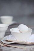 Eier in weisser Porzellanschale auf Holztisch