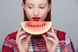 A young woman holding a slice of watermelon