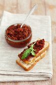 Dried tomato pesto on slice of white bread and in a jar