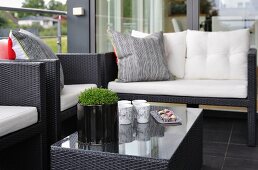 Elegant outdoor furniture made from black all-weather wicker on black tiled floor