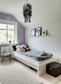 Tray table next to bed in girl's attic bedroom with white and pale lilac walls