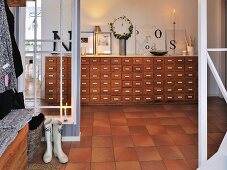 Tiled hallway with glass partitions; view of decorative letters on vintage apothecaries' cabinet