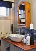 Rustic mirrored cabinet above washstand with varnished beach worksurface and stone splashback