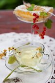 Linden blossom tea, honeycomb and redcurrants on a garden table