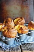 Cheese soufflés in a baking tin on a tea towel on a wooden table