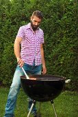 Junger Mann grillt Lachsforellen Filet im Garten