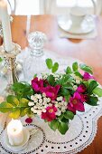 Bouquet of garden flowers and candles on lace doily