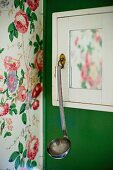 White cabinet with ladle hanging from handle mounted on green wall