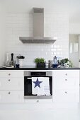 Black and white kitchen counter with stainless steel extractor hood and subway tiles on wall